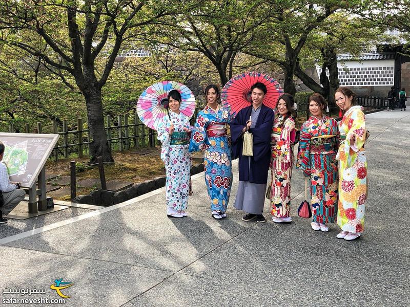 توریست هایی که کیمونو لباس سنتی ژاپن رو می پوشند و در ورودی قلعه عکس میگیرند.