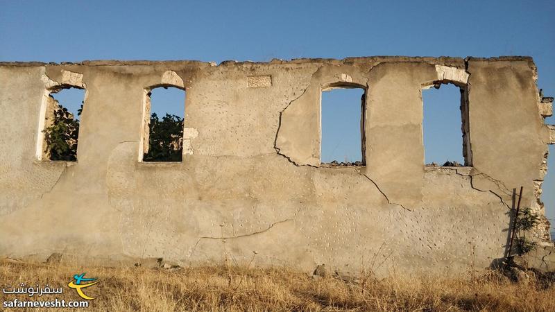 دیوار ساختمان مخروبه که لوحی از اسماء متبرکه شیعیان و سال ۱۹۵۲ بر خود دارد